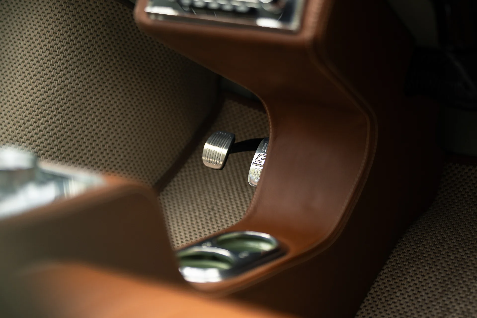Tan leather footwell with brushed aluminium pedals and woven floor mat